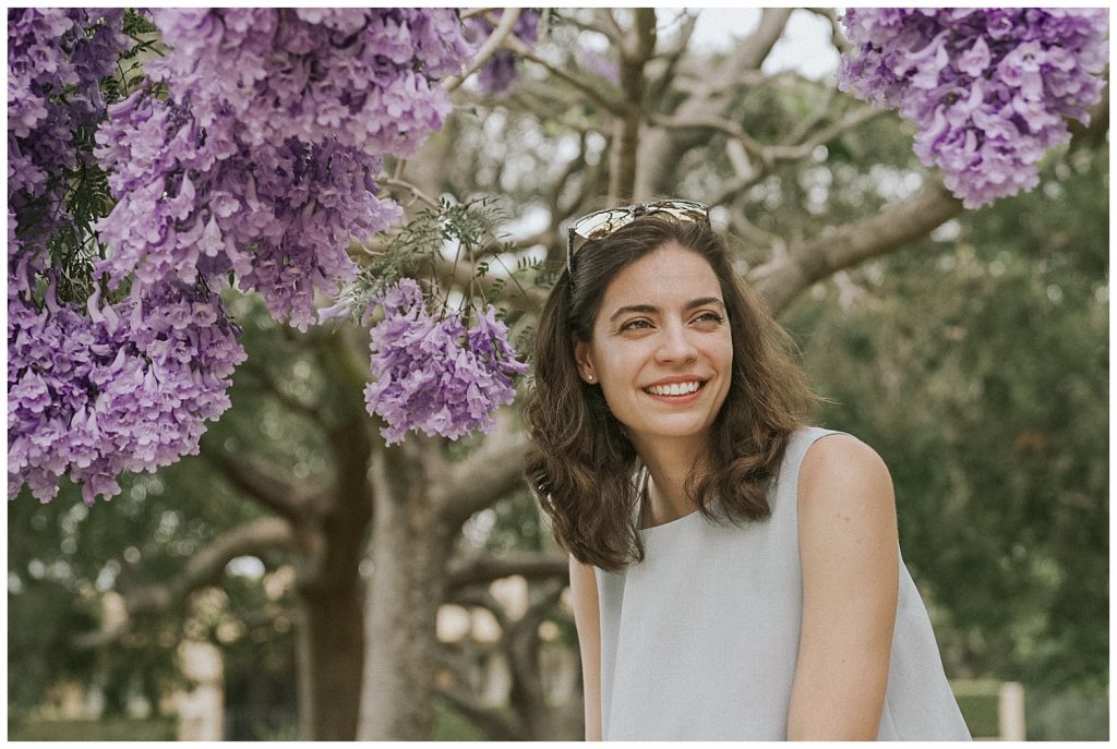 woman-smiles-under-jacaranda-tree-photo