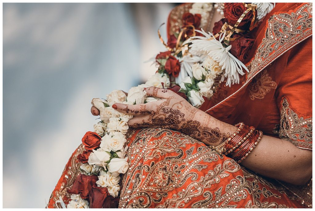 mehendi-on-brides-hands-holding-flower-garland-photo